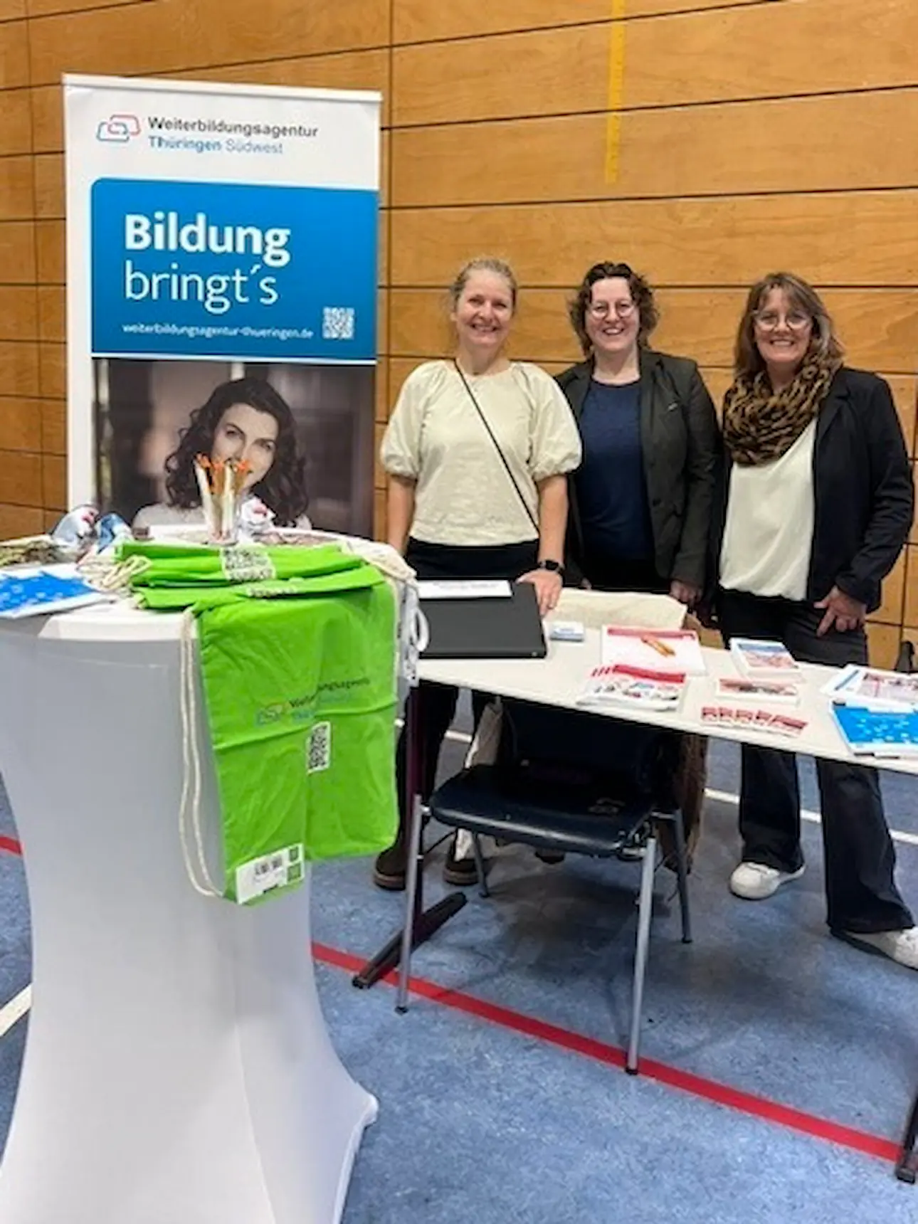 Drei Beraterinnen stehen hinter einem Informationsstand der Weiterbildungsagentur Thüringen Südwest mit Broschüren und  weiteren Informationsmaterial.